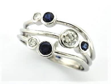 Signature Brook Wave Ring re-designed using diamonds from client's existing ring with new Sapphires as a Three Wave Ring.  Client chose these mid blue gemstones,  from a selection, as she felt preferred the contrast with white gold.